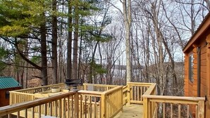A wooden deck with railings, a picnic table, and a grill. - 114) Pelican Log Cabin. Close to Hocking Hills State Park and more! (Logan)