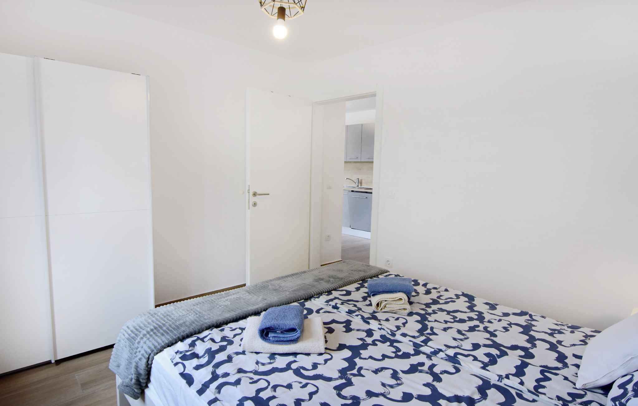 Une chambre à coucher avec un lit, une armoire et une salle de bain visible à travers une porte ouverte.