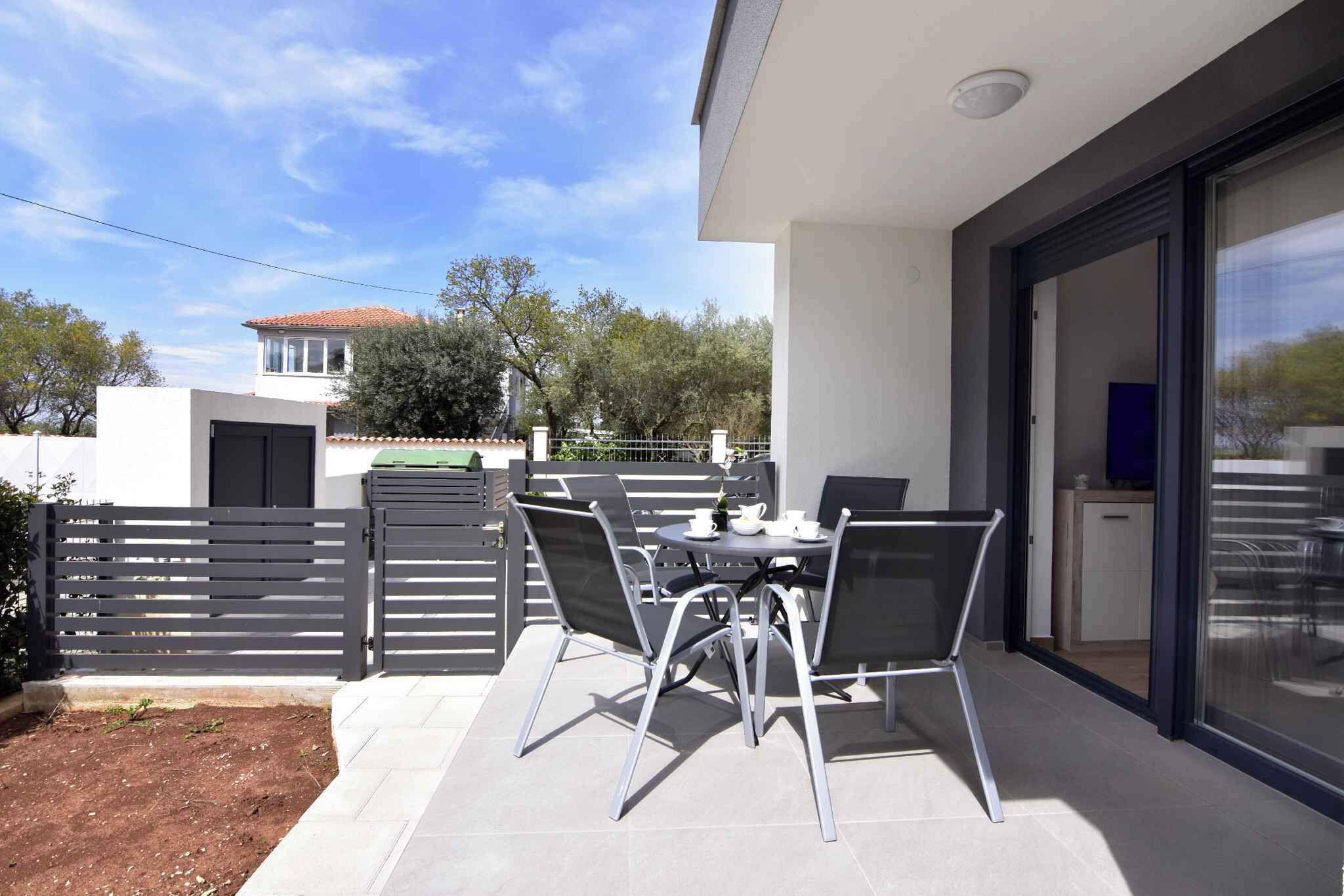 An outdoor patio area with a table and chairs, a sliding glass door leading to a kitchen, and a fenced garden.