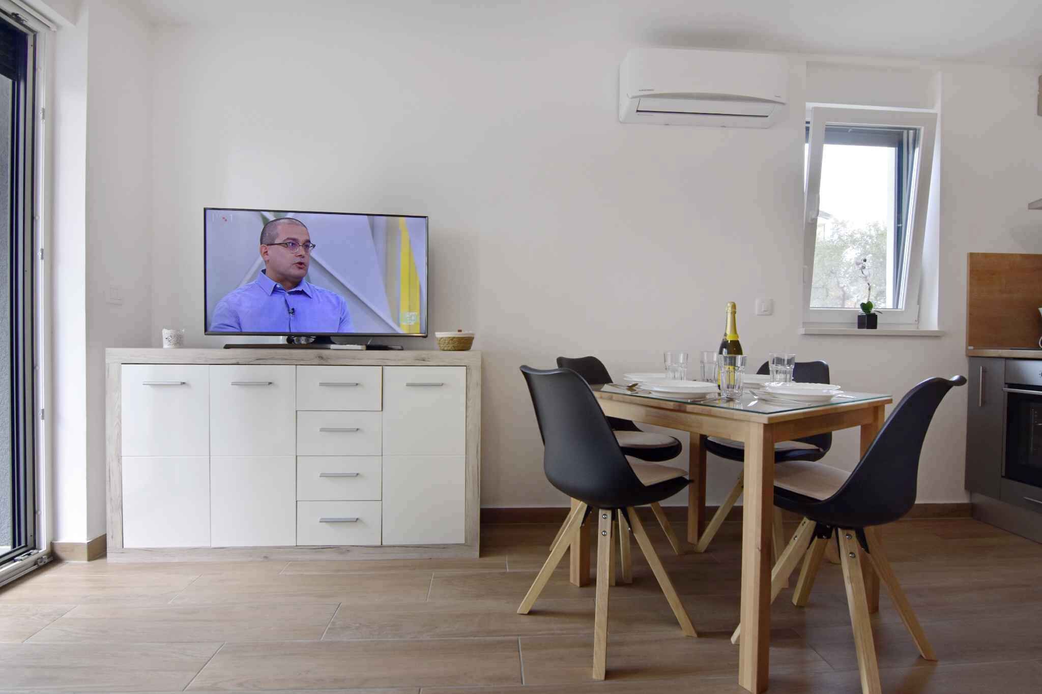A modern kitchen with a dining area, a TV, and a window.