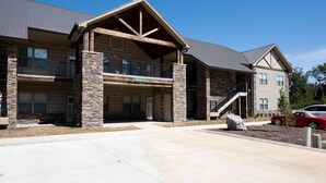 A two-story building with a stone facade, a covered front porch, and a visible garage. - It is Springtime in TN- comfortable, clean, in a gated community & near food! (Townsend)