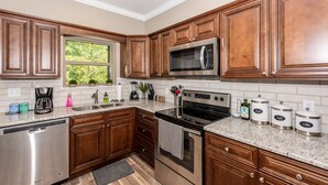 A modern kitchen with wooden cabinets, stainless steel appliances, and a window providing natural light. - It is Springtime in TN- comfortable, clean, in a gated community & near food! (Townsend)