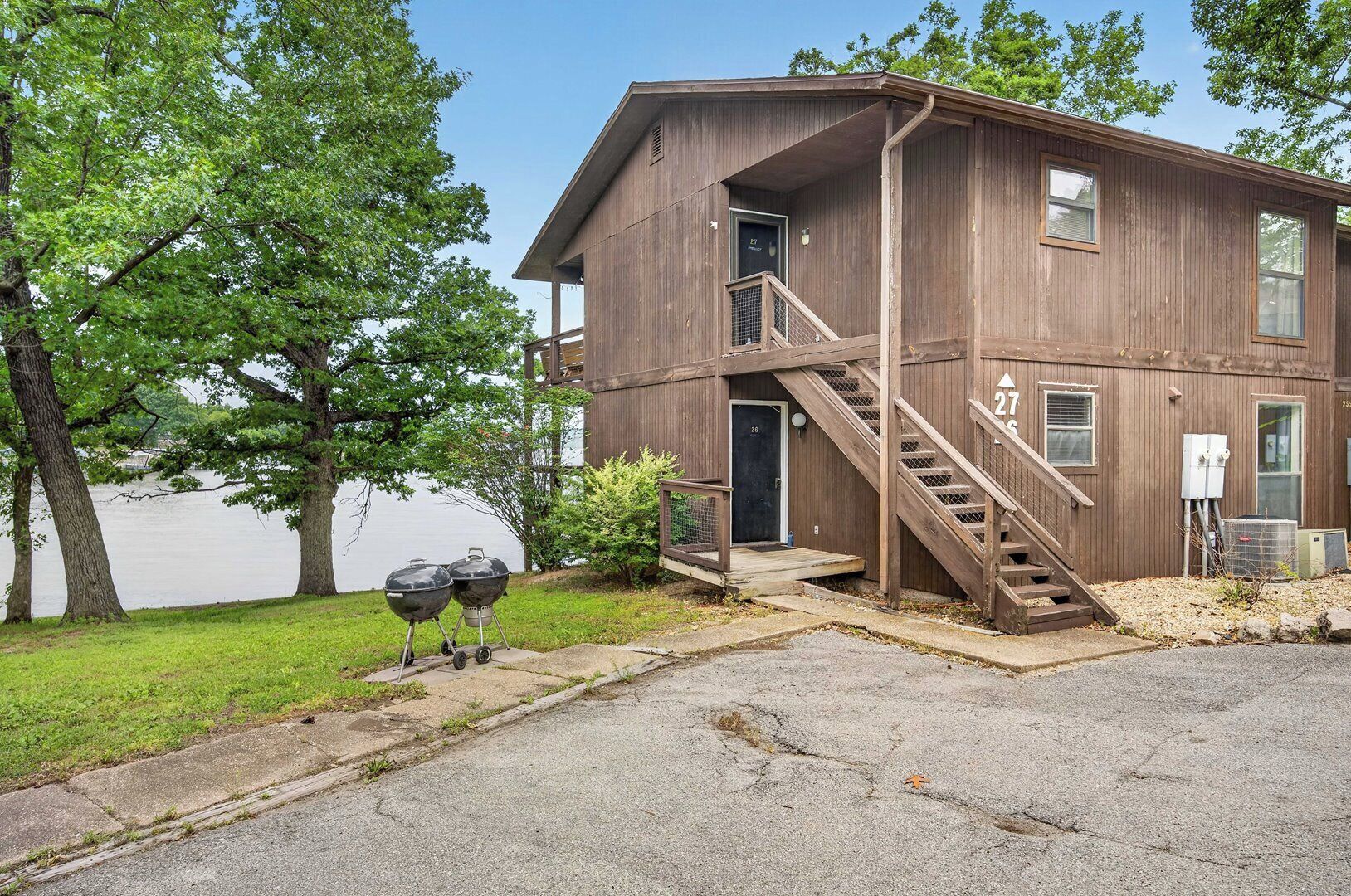A two-story wooden building with a staircase, a door labeled '27', and a view of a lake.
