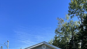 A single-story house with a gabled roof, a front door with a glass panel, and a small window on the right side. - Cozy quiet Cottage (Deer Isle)