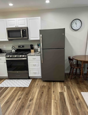 Enjoy cooking in this well-equipped kitchen with a refrigerator, microwave, and gas stove, along with a dining table and chairs.
