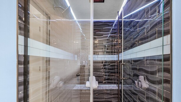 Ein modernes Badezimmer mit Glaswänden, Fliesenboden und einer sichtbaren Dusche.