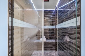 Une salle de bain moderne avec des murs en verre, un sol carrelé et un espace douche bien délimité.