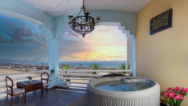 A room with a hot tub, a wooden table with chairs, and a view of the beach. - El Capitan Resort (Playas de Rosarito)