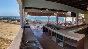A seaside bar with a view of the ocean, outdoor seating, and a kitchen area. - El Capitan Resort (Playas de Rosarito)