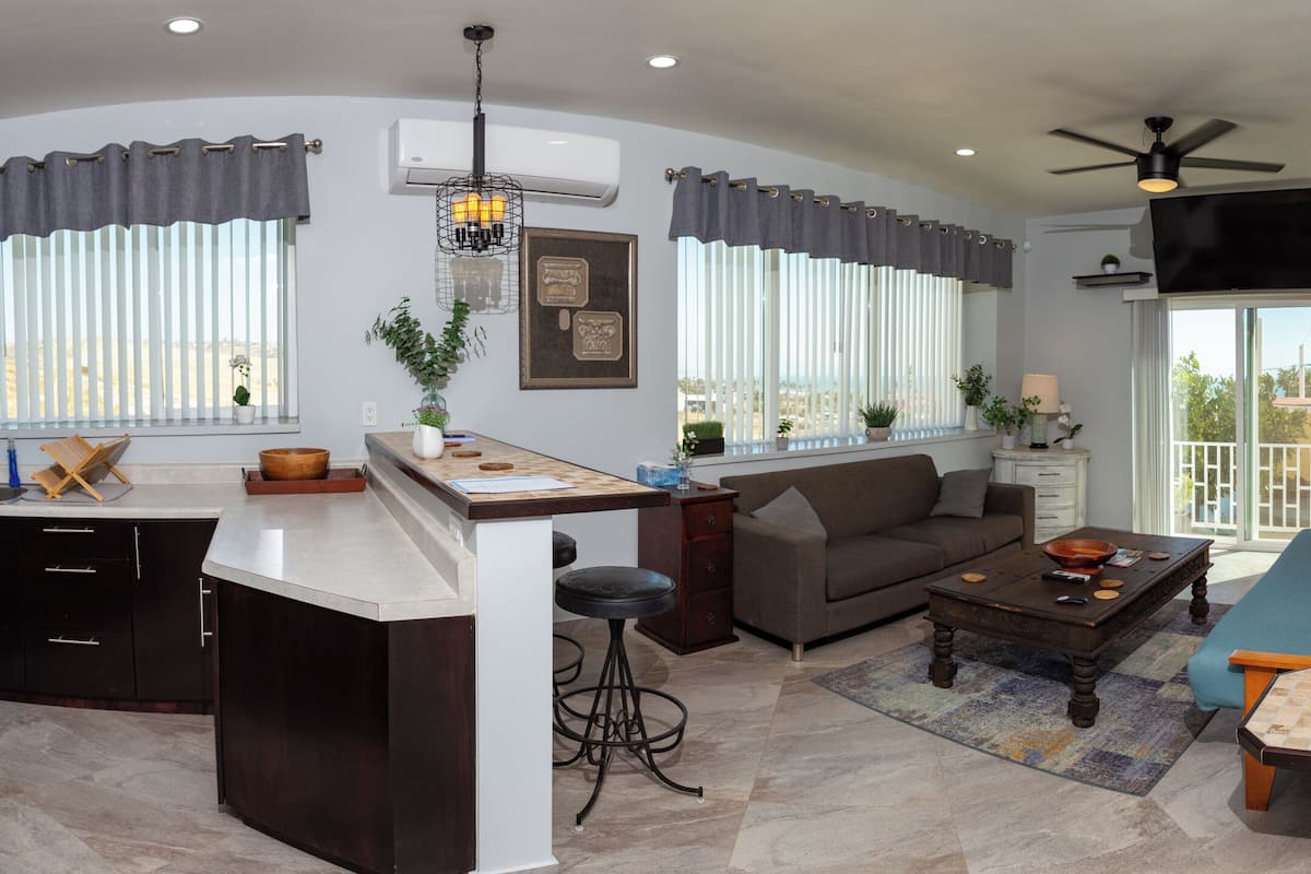 A modern living room with a kitchen area, a sofa, a coffee table, and a TV.