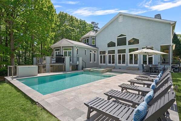 A swimming pool with lounge chairs and a covered patio area.