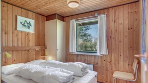 A wooden-paneled bedroom with a bed, a window with curtains, a small table, and a chair. - 3 bedroom lovely home in Sjællands Odde (Sjællands Odde)