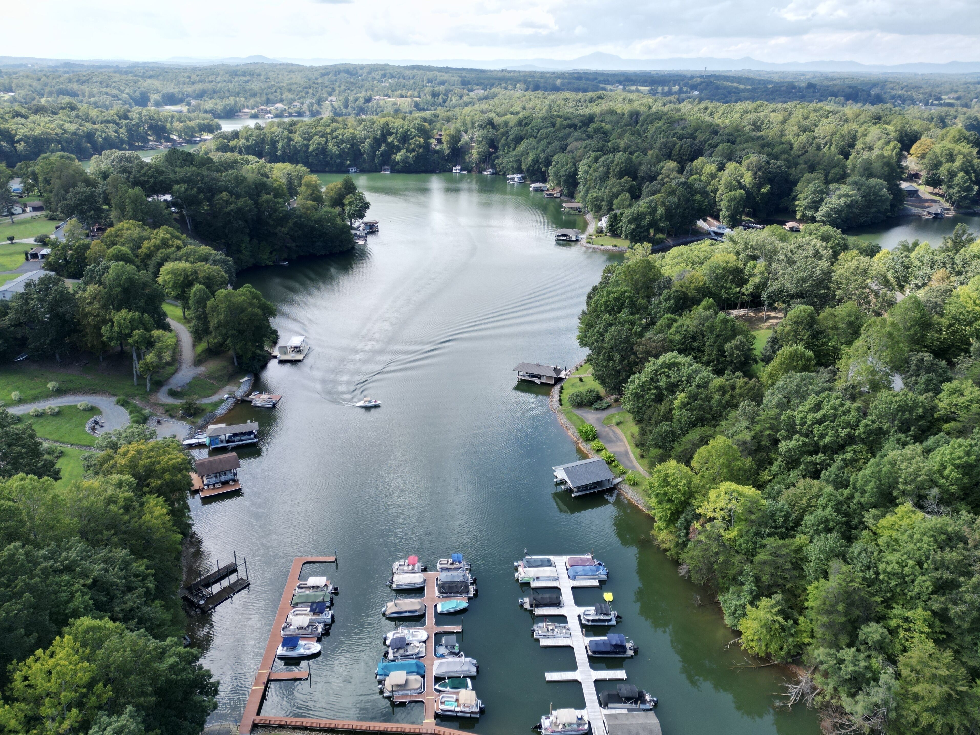 Un port de plaisance où sont amarrés des bateaux, entouré d’une végétation luxuriante et bordé par une rivière.
