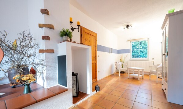 A kitchen with a white cabinet, a wooden door, and a window with a view of trees. - Ferienhaus Luppath, Deutschland (Poseritz)
