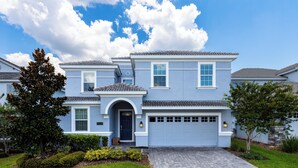 A two-story house with a blue exterior, a front garage, and a well-maintained lawn.