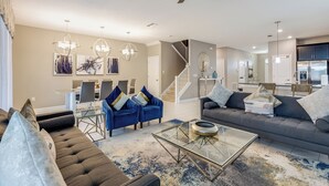A spacious living room with a modern sofa, a glass coffee table, and a dining area with chairs.