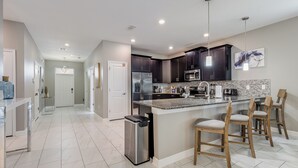 A modern kitchen with dark cabinets, stainless steel appliances, and a marble countertop.
