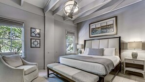 A bedroom with a large bed, a bench, a chair, and a nightstand. - Great Location Downtown, Heated Pool Access (Savannah)
