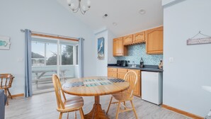 A modern kitchen with wooden cabinets, a dining table with chairs, and a view of the outdoors through a large window. - 1747 - Resting Beach Place, Pool, Hot Tub & Game Room | Sleeps 15 in Corolla (Corolla)
