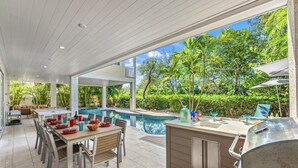 Une terrasse extérieure avec une piscine, un coin repas et un barbecue.