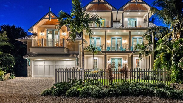 Une maison à plusieurs étages avec un garage, un balcon et une entrée bien éclairée.