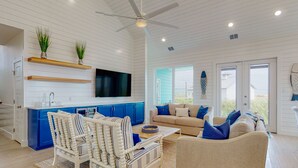 A spacious living area with a white ceiling, a ceiling fan, and a large window. - Golf Cart Included, Shared Pool, Hot Tub, Boardwalk to the Beach (Port Aransas)