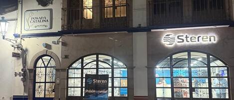 Un edificio de dos pisos con ventanas arqueadas y un letrero que dice 'POSADA CATALINA'.