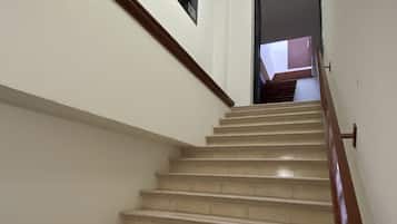 Una escalera con barandilla de madera y peldaños color beige que conducen a una plataforma.