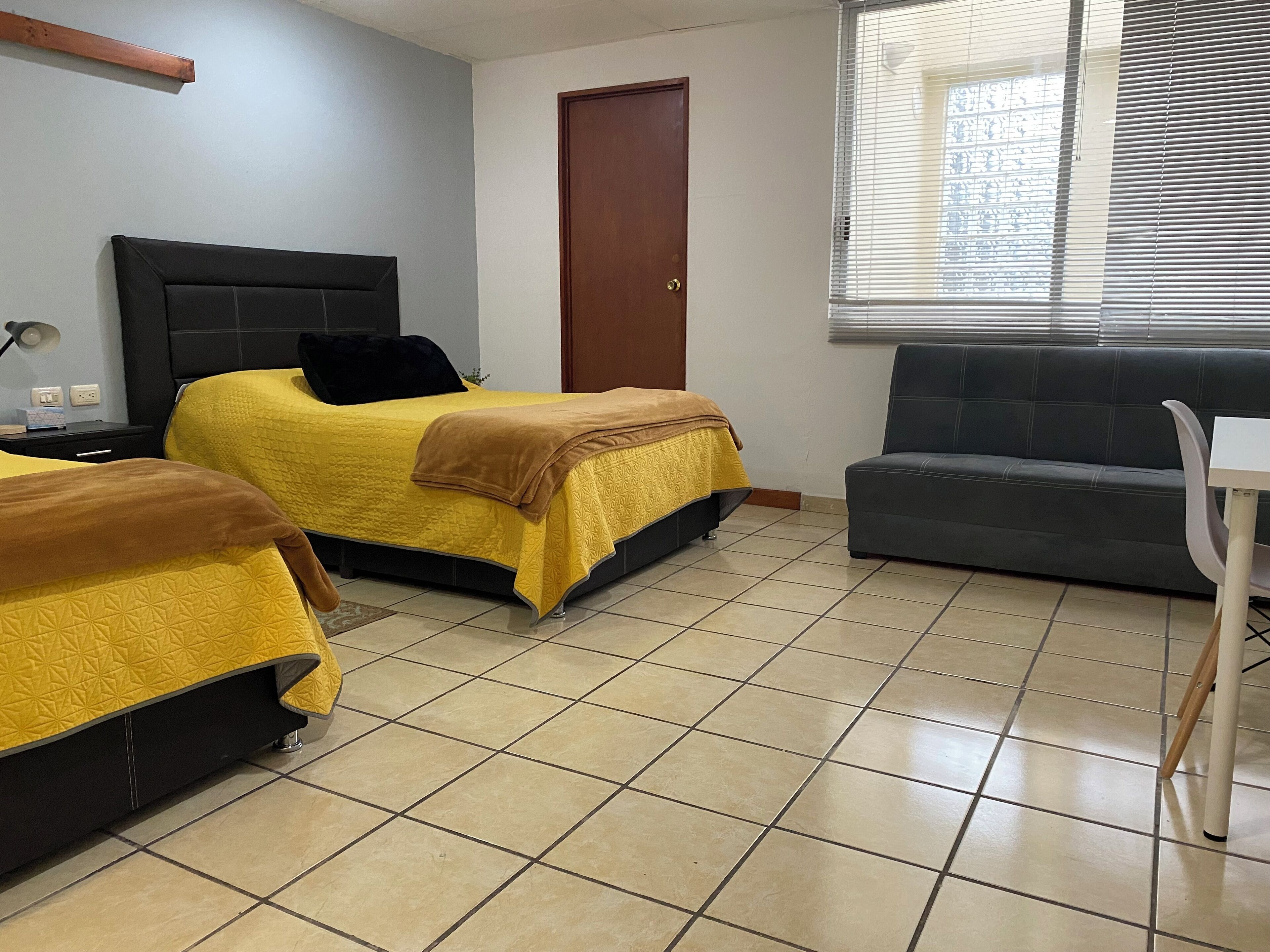 A room with two beds, a sofa, a table, and a door.