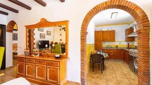A kitchen with a brick archway, wooden cabinets, and a tiled floor. - Cortijo La Reina by Solset (Torrox)