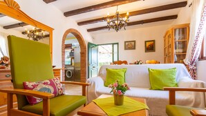 A cozy living room with a green armchair, a wooden coffee table, and a white sofa with green cushions. - Cortijo La Reina by Solset (Torrox)