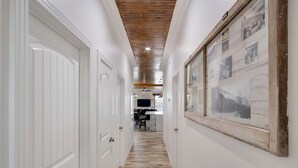 A hallway with white doors, a wooden ceiling, and a wall with framed pictures. - Historical Florence apartment (Florence)