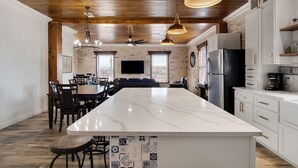 A spacious kitchen with a large island, white cabinetry, and a stone accent wall. - Historical Florence apartment (Florence)