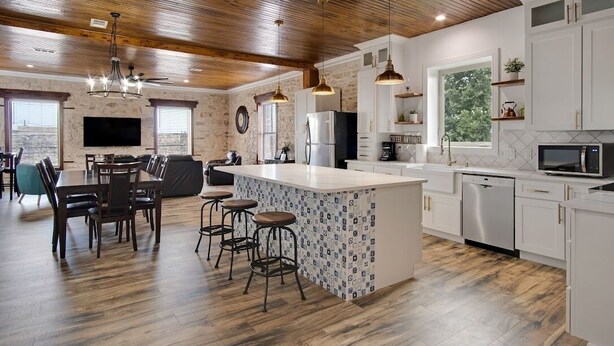 A modern kitchen with a central island, bar stools, and a dining area with a large table and chairs. - Historical Florence apartment (Florence)