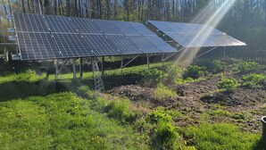 Solar panels in a field with trees in the background. - South Side Inn - Burlington (South Burlington)