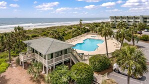 A resort with a pool, beachfront view, and a building with a balcony overlooking the ocean.