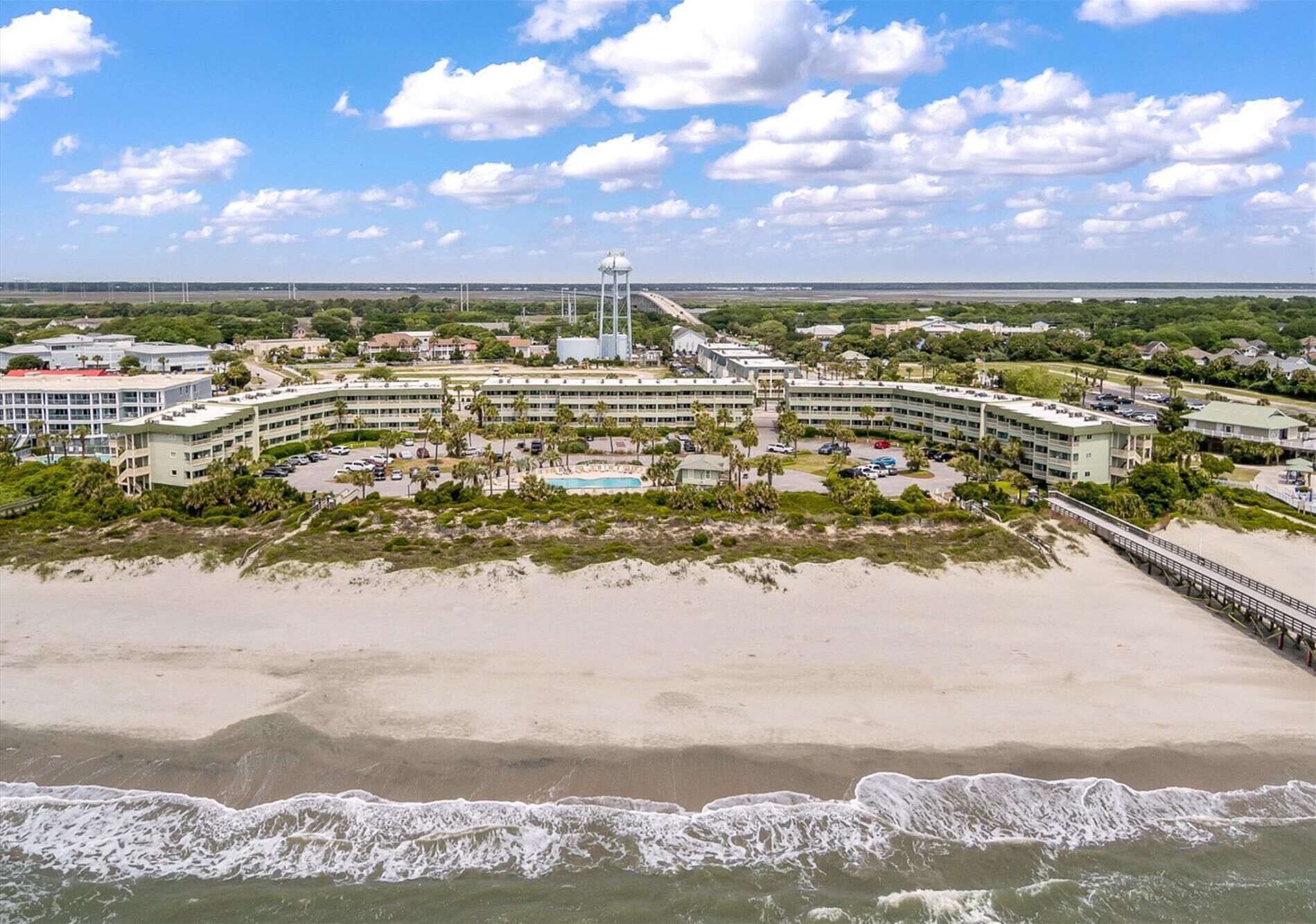 A coastal hotel with multiple buildings, a beach, and a pier.