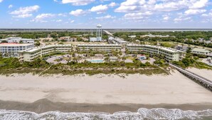 A coastal hotel with multiple buildings, a beach, and a pier.