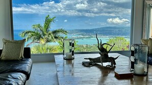 Una habitación con un gran ventanal que ofrece vistas al océano y palmeras.