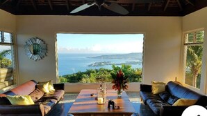 Una habitación con un amplio ventanal con vistas al mar, amueblada con dos sofás y una mesa de centro.