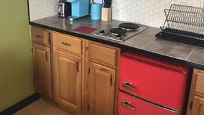 A kitchen with wooden cabinets, a red refrigerator, a stainless steel microwave, a coffee maker, and a knife block. - Cozy Efficiency Studio/A near DownTown (San Antonio)