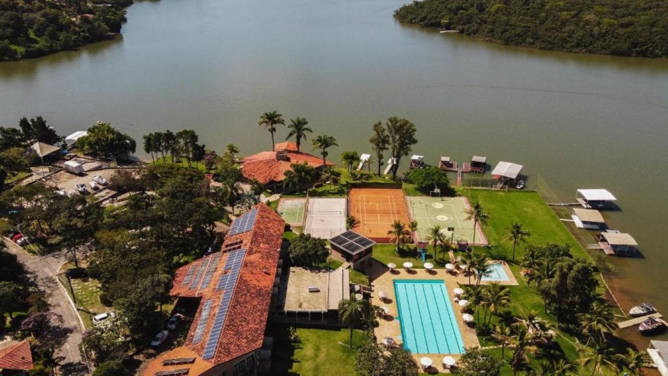 Vista aérea de un resort con piscina, canchas de tenis y un muelle.