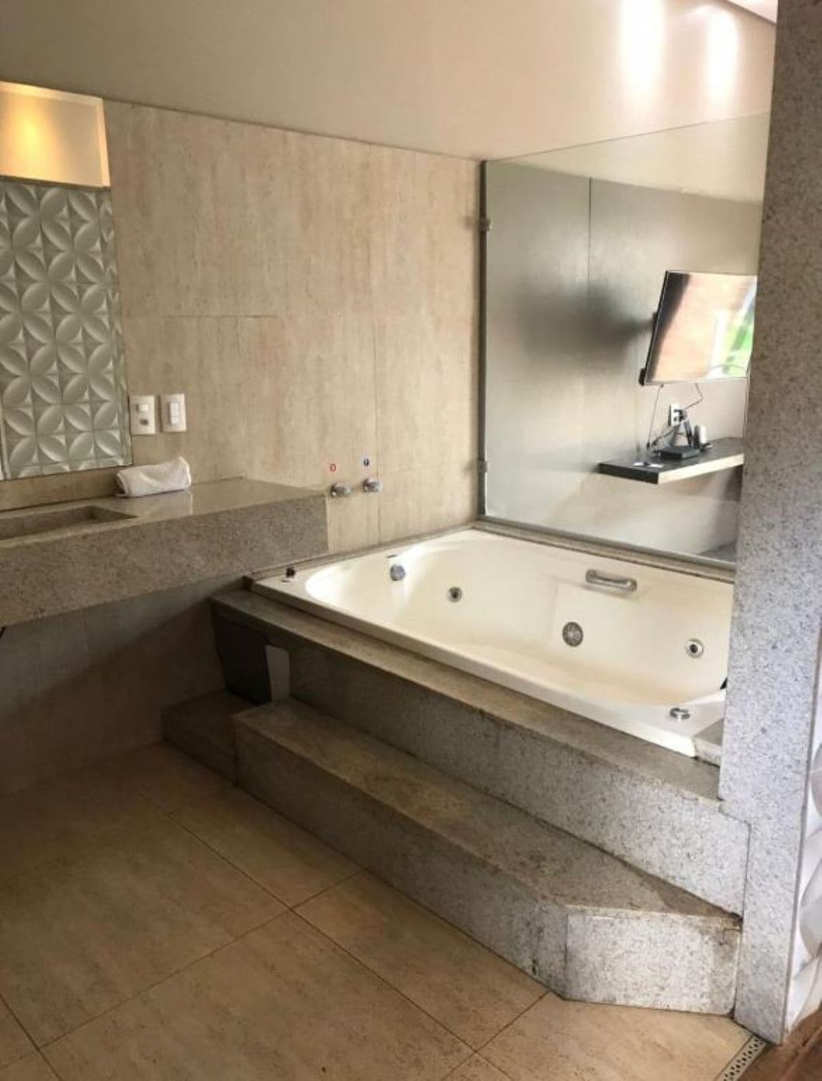 Une salle de bain moderne avec une baignoire sur pieds, un grand miroir et un revêtement mural texturé.