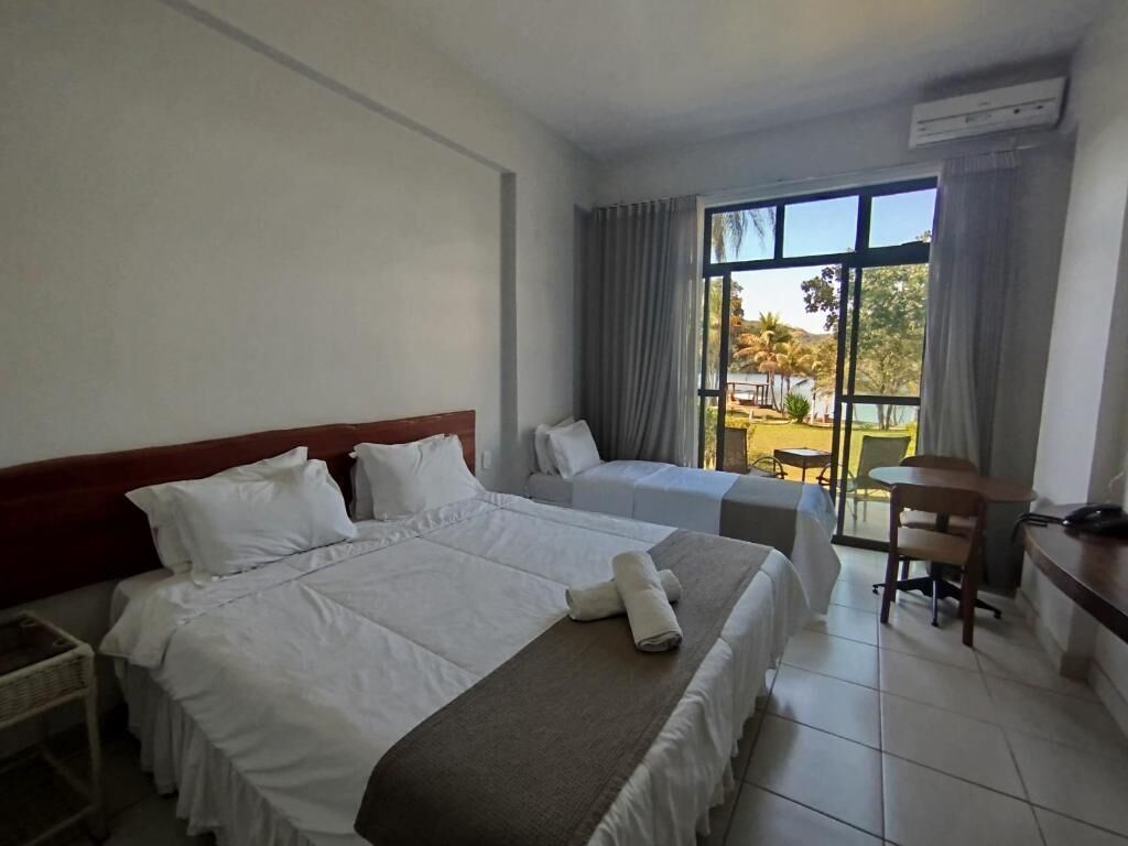 A hotel room with two beds, a desk, and a view of the outdoors.
