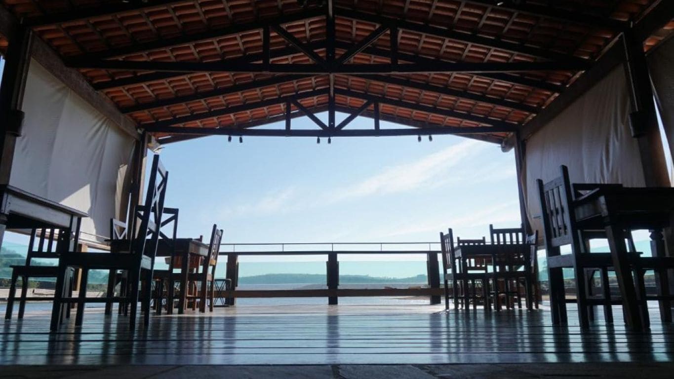Uma área descoberta coberta com vista para o mar, com um deck de madeira e espaços para sentar.