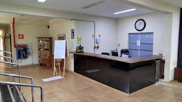 Zona de recepción con mostrador, un reloj y una pizarra.