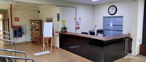 Zona de recepción con mostrador, un reloj y una pizarra.