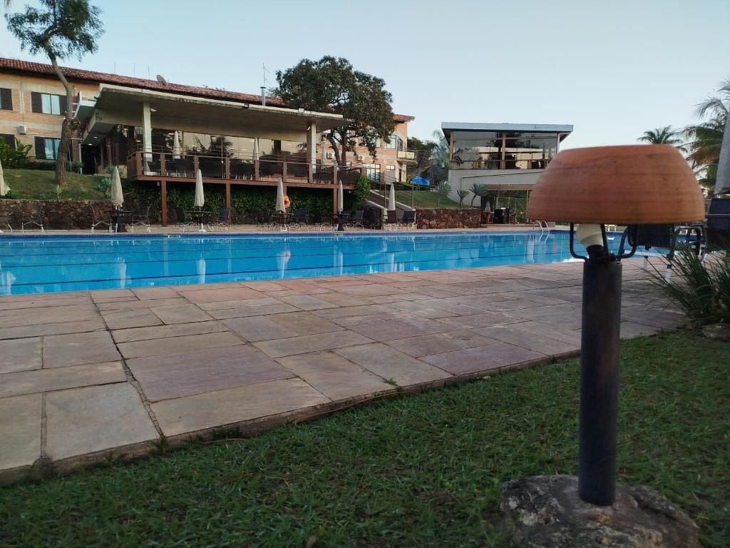 Una piscina con solárium de piedra, un farol y un edificio al fondo.