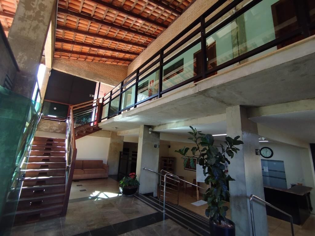 Un interior de varios niveles con una escalera, un mostrador de recepción y una planta.