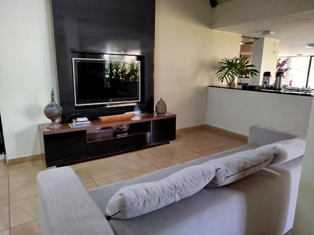 Una sala de estar con una televisión de pantalla plana, un sofá, una mesa de centro y una planta.